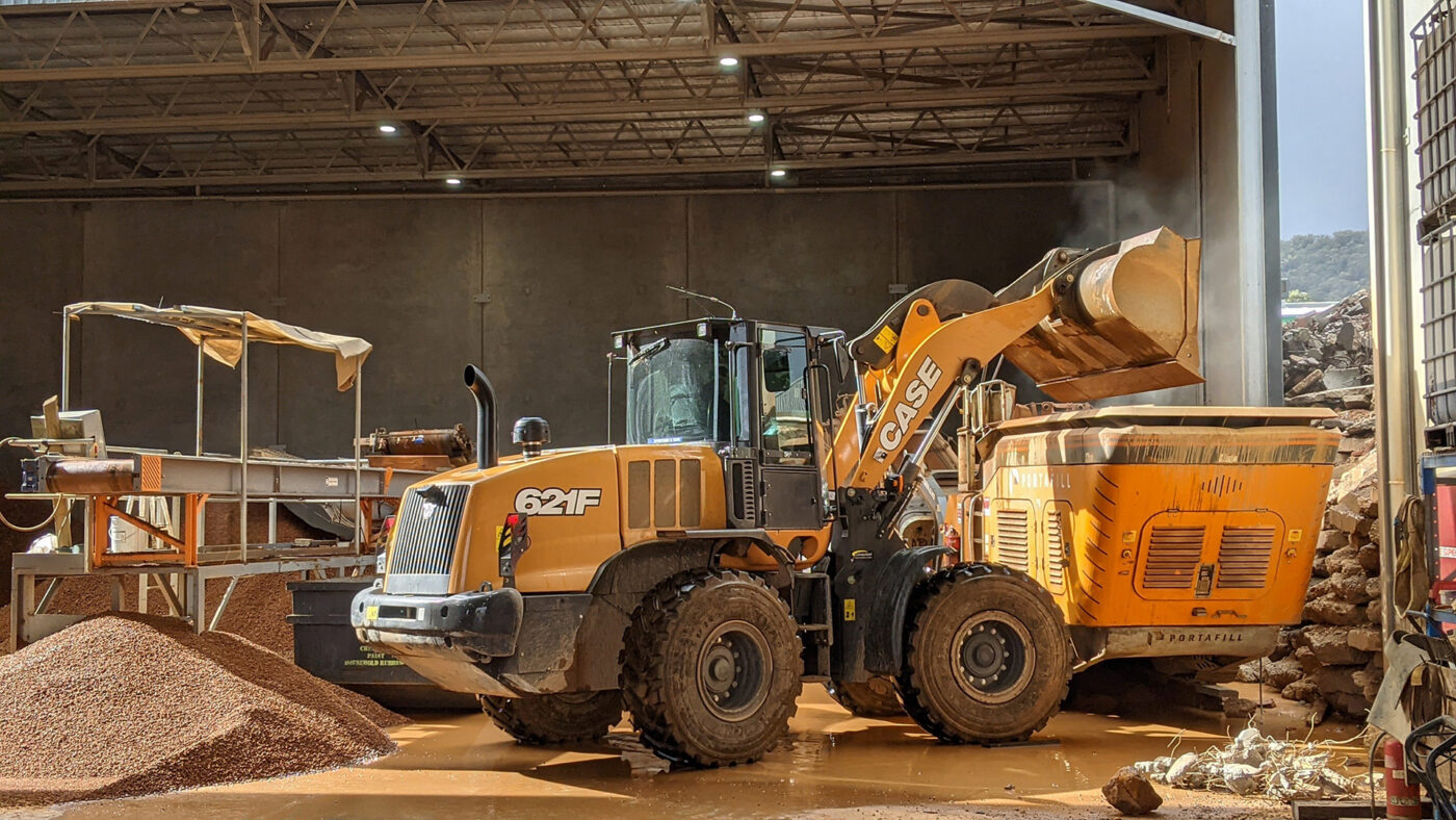 a yellow large front end loader filling a truck with gravel